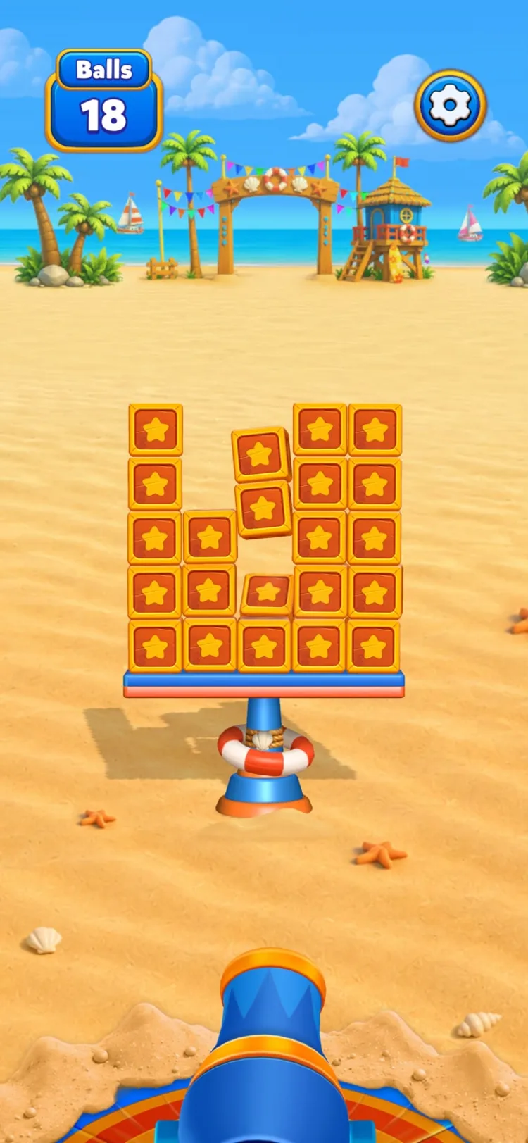 A neat wall of star-stamped blocks stacked on the beach platform, with 18 balls left in the counter and the cannon aimed from below